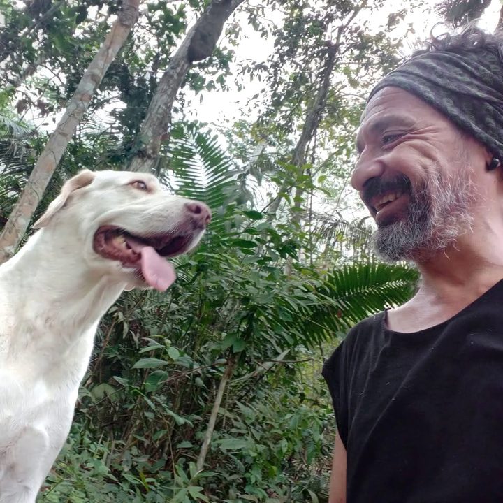 Alberto sonriendo junto a su perra blanca en la selva